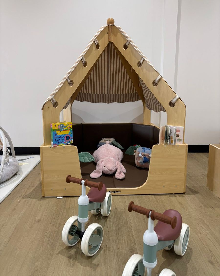 A timber cubby house with cushions in the Peony room